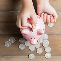 Person putting coins into a piggy bank